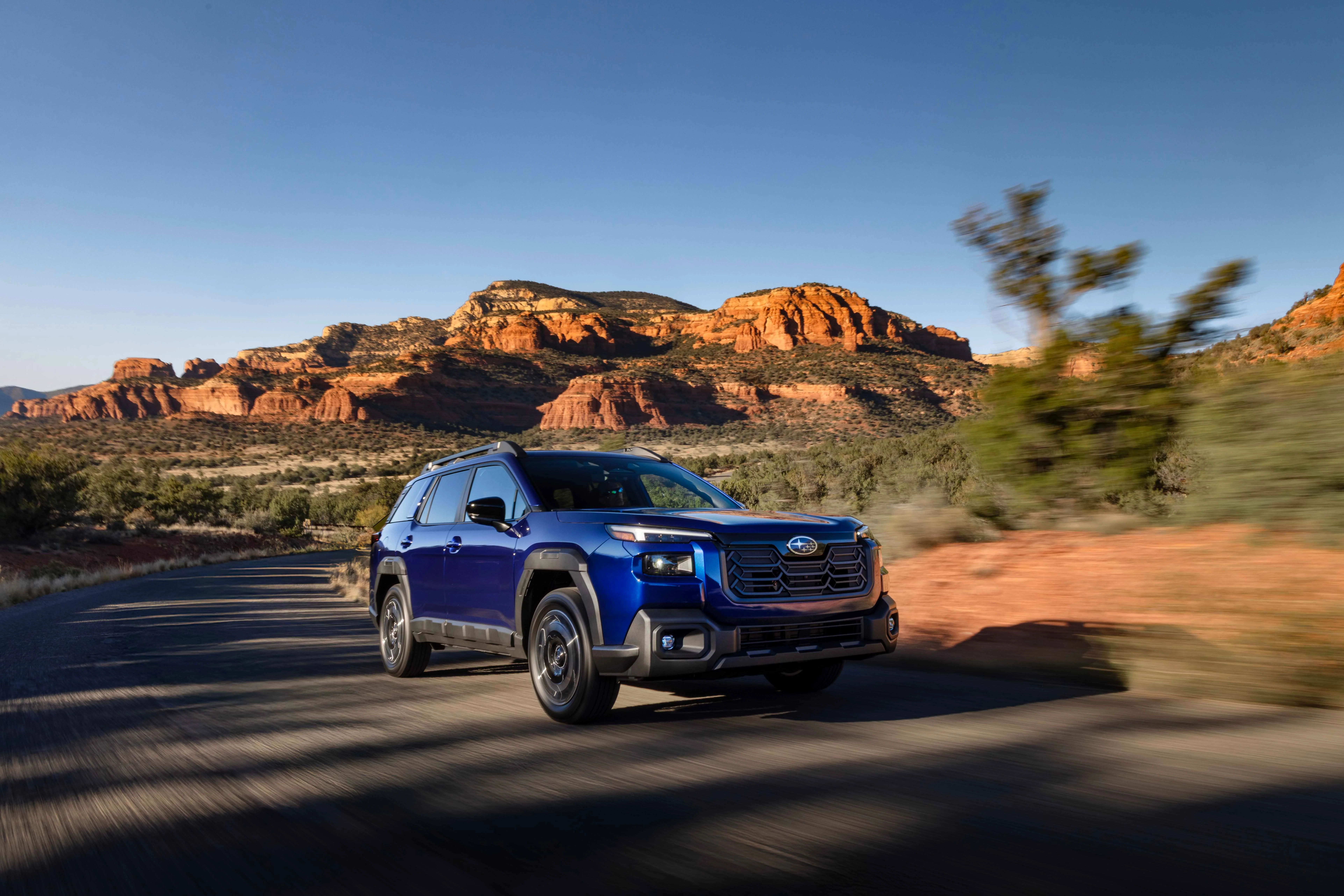 Front profile of a 2026 Subaru Outback driving on a scenic road.