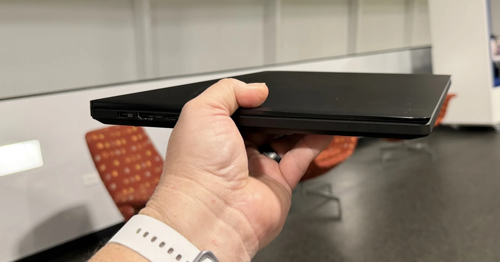 A laptop on its side, held, with ports visible