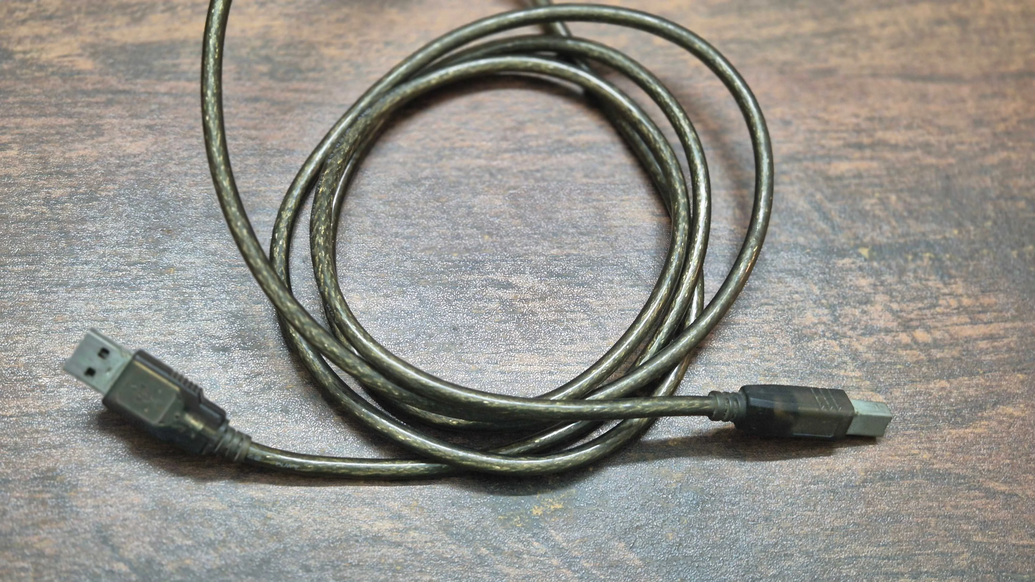A USB Type-A to USB Type-B cable on a table.