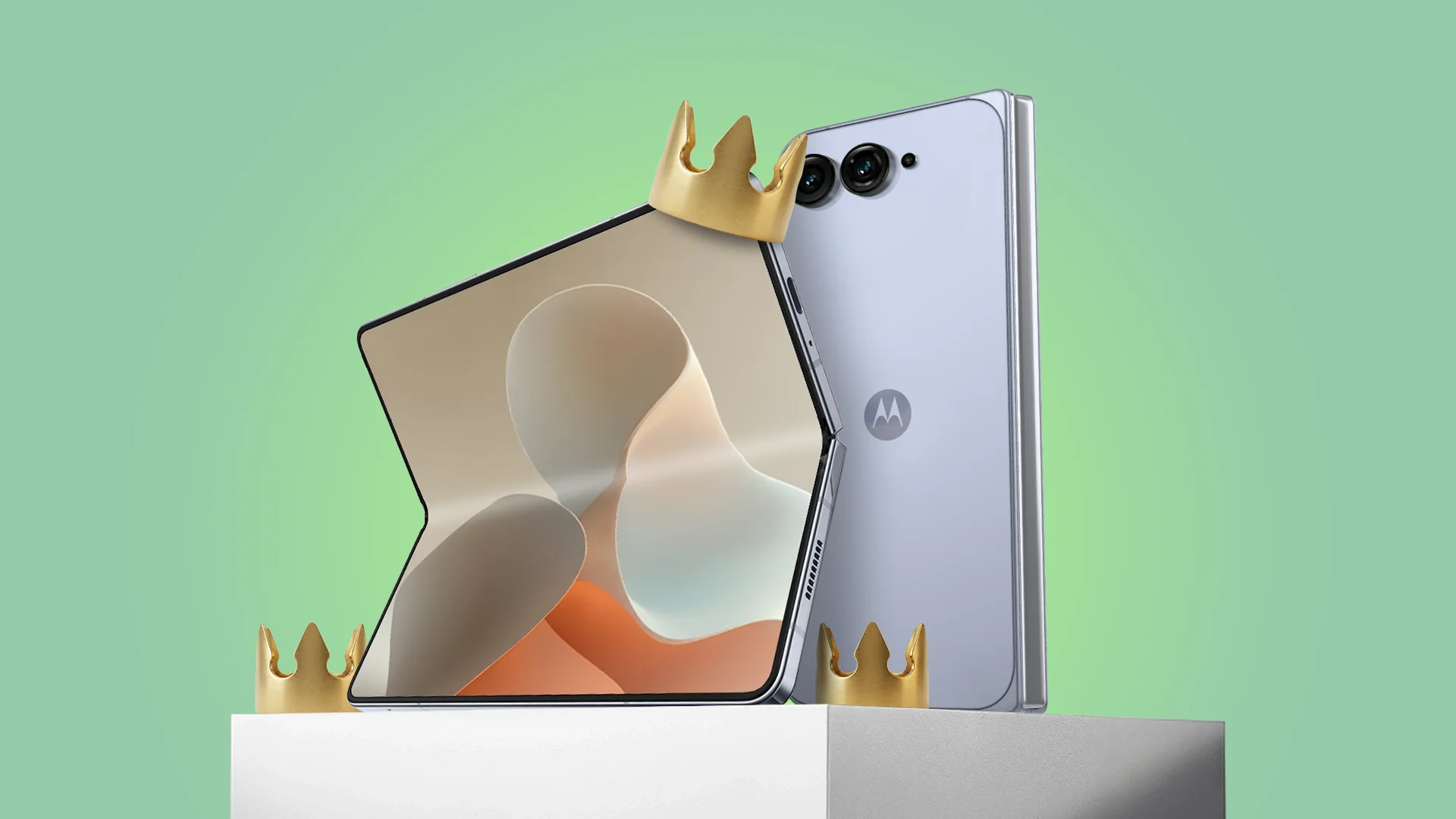 Motorola foldable smartphone standing on a white pedestal with a gold crown resting on its corner, against a green background.