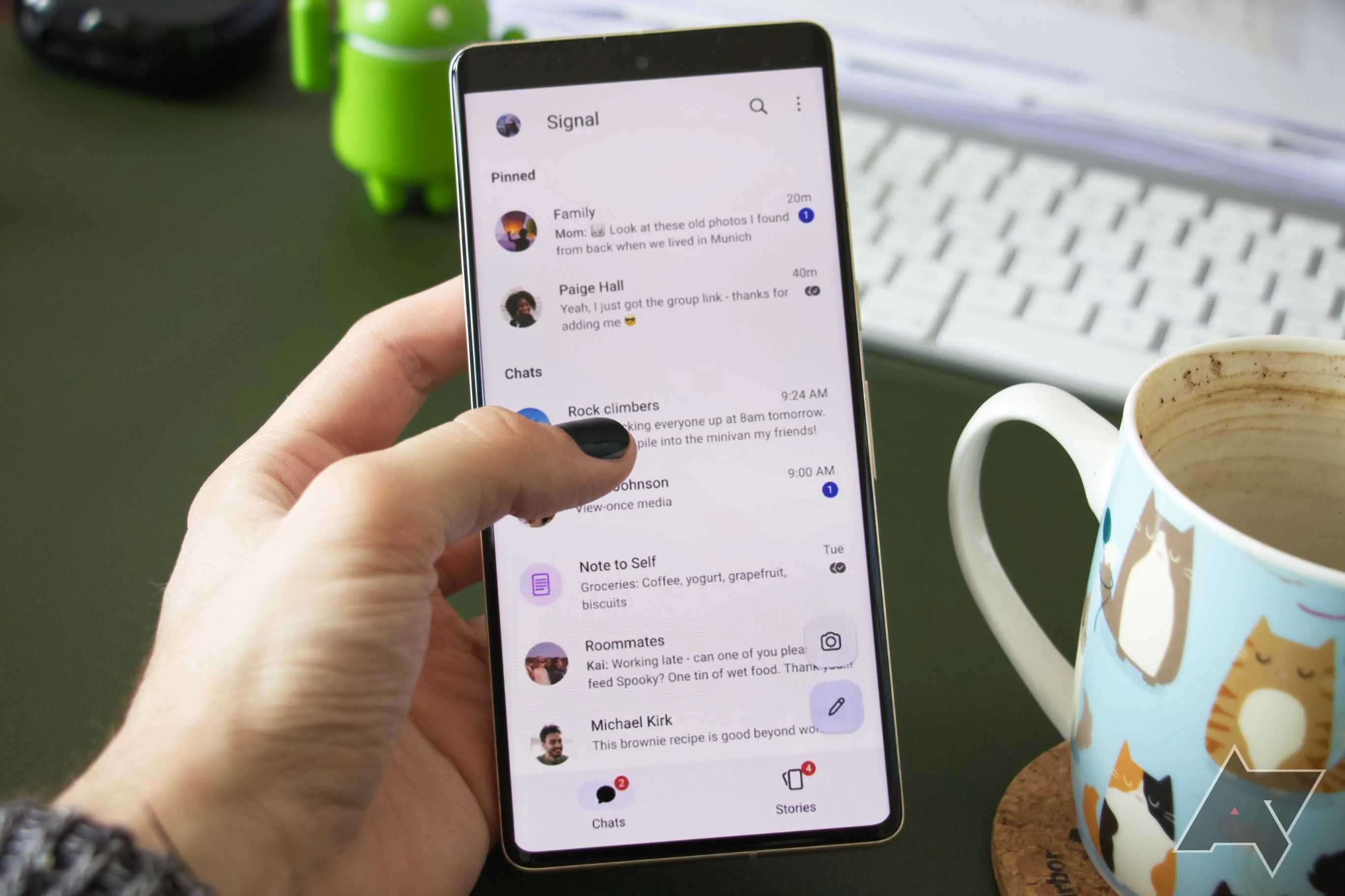 A person is holding a Google Pixel 7 Pro, interacting with the Signal chat overview