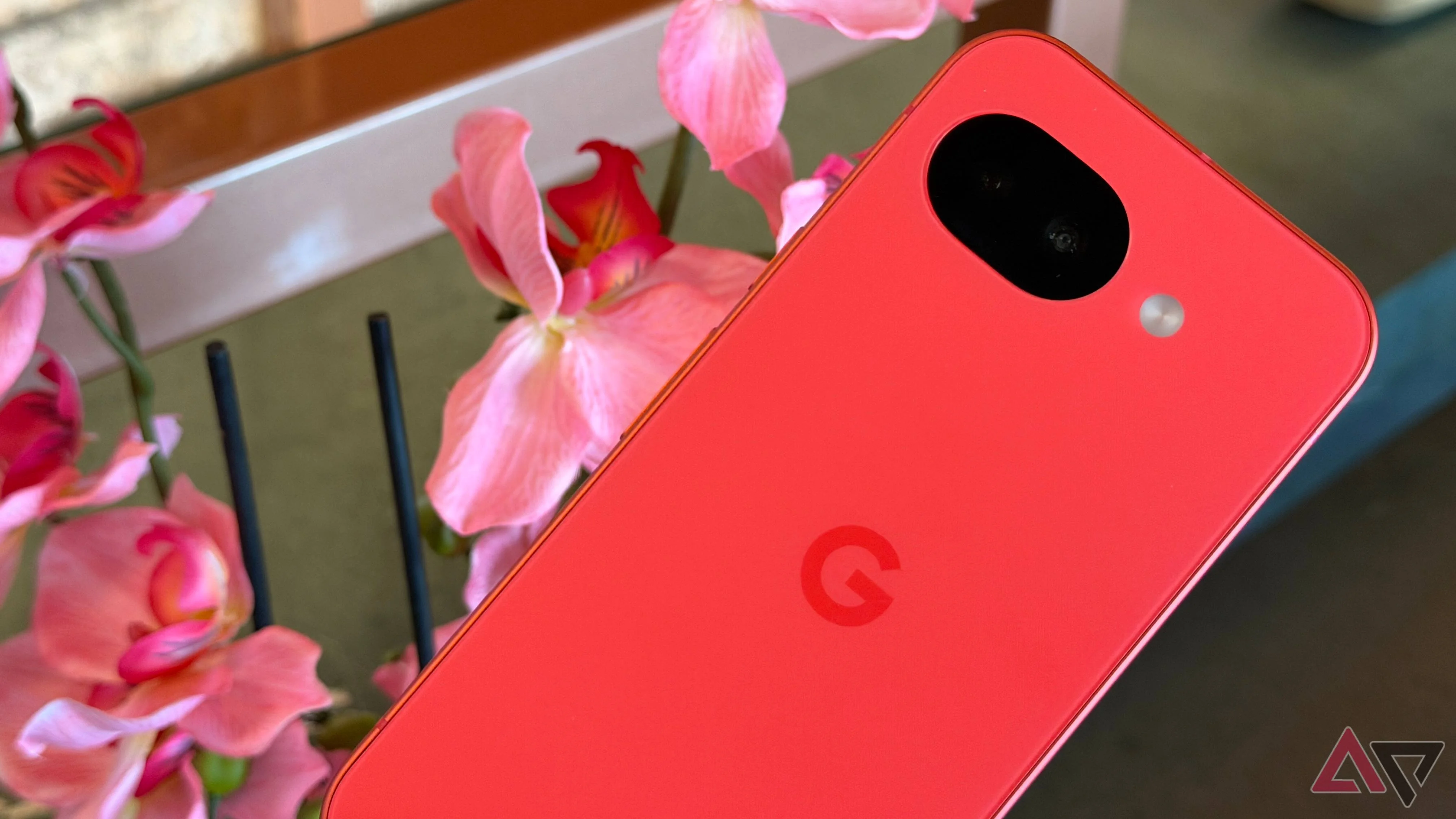 Google Pixel 10a in Berry next to pink flowers